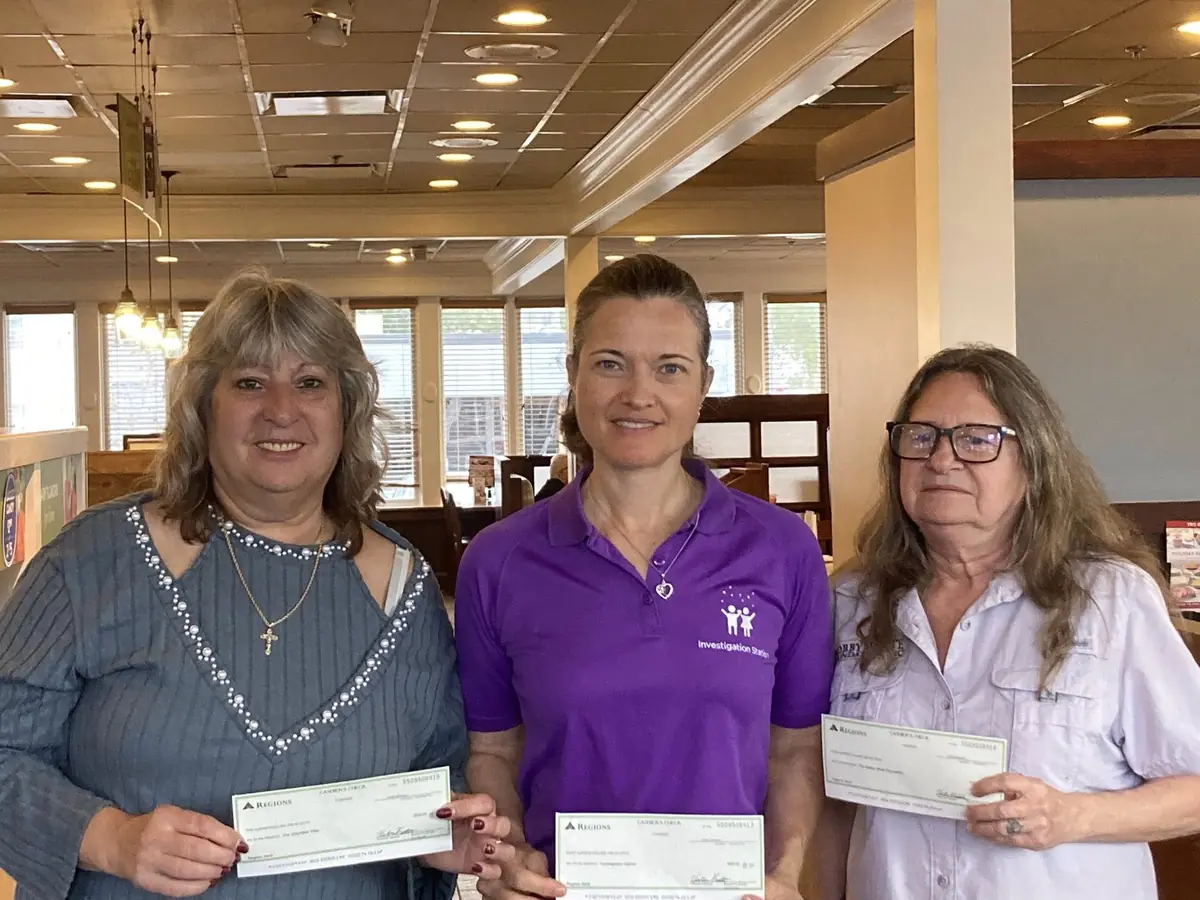 Three TPBG members holding donation checks for local non-profits